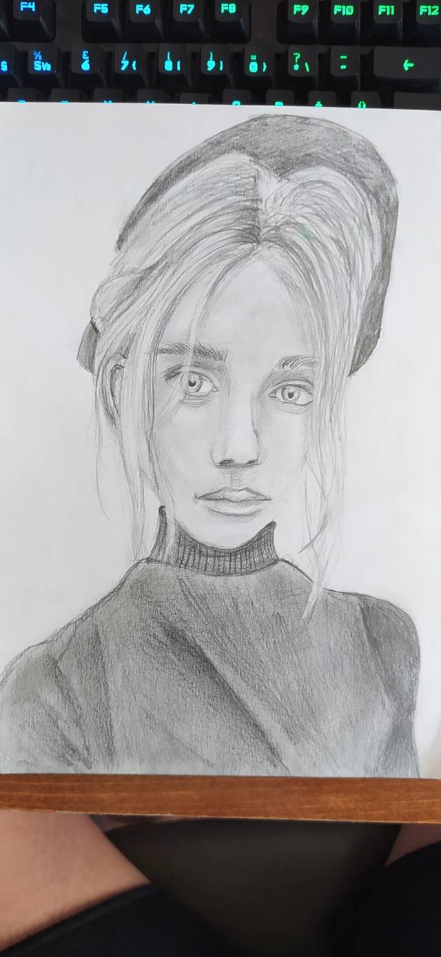 Graphite portrait of a young woman with her hair tied up, wearing a turtleneck, on a spiral pad in front of a keyboard.