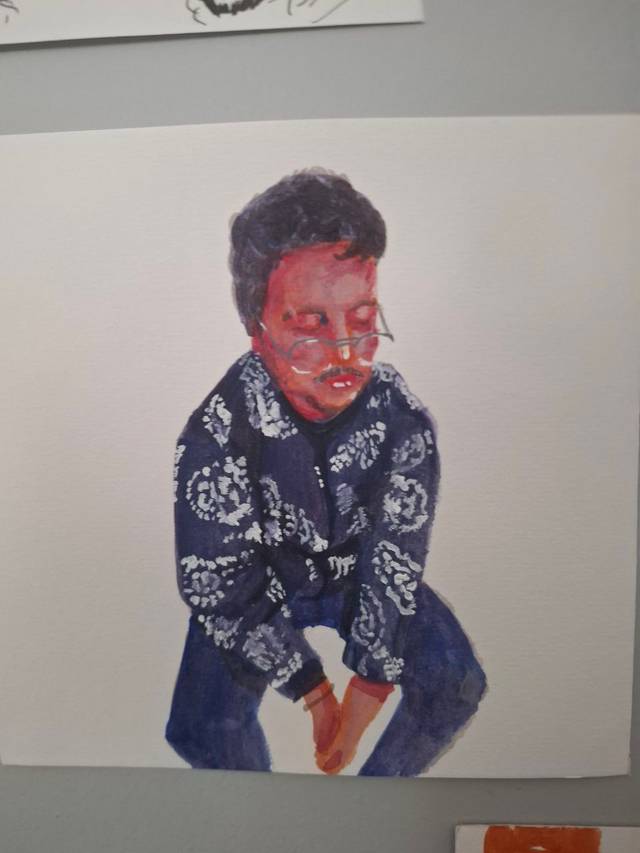 Watercolor portrait of a person with dark hair and glasses crouching in a blue floral shirt, on white paper.